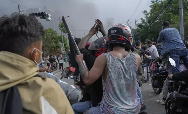 A protester rides on two wheelers carrying a firearm with others during a protest against a social media ban and corruption in Kathmandu, Nepal, Tuesday, Sept. 9, 2025. (AP Photo/Niranjan Shrestha)