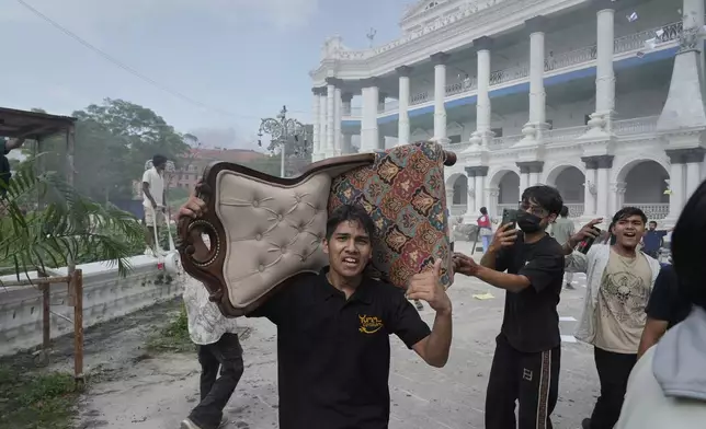A protester carries a chair from the Singha Durbar, the seat of Nepal's government's various ministries and offices during a protest against social media ban and corruption in Kathmandu, Nepal, Tuesday, Sept. 9, 2025. (AP Photo/Niranjan Shrestha)