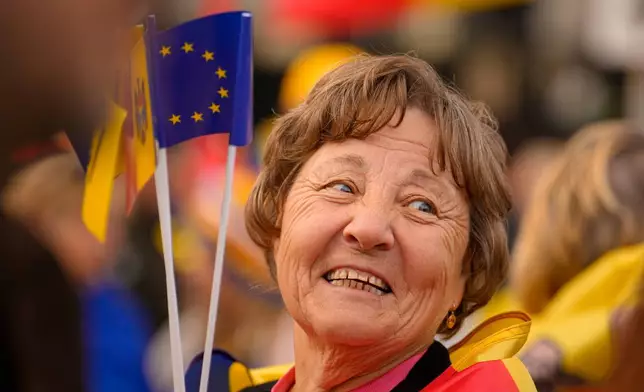 A woman smiles as she holds Moldovan and EU flags during a pro-EU rally of the ruling Party of Action and Solidarity (PAS), in Chisinau, Moldova, Friday, Sept. 26, 2025, ahead of parliamentary elections taking place on Sept.28. (AP Photo/Vadim Ghirda)