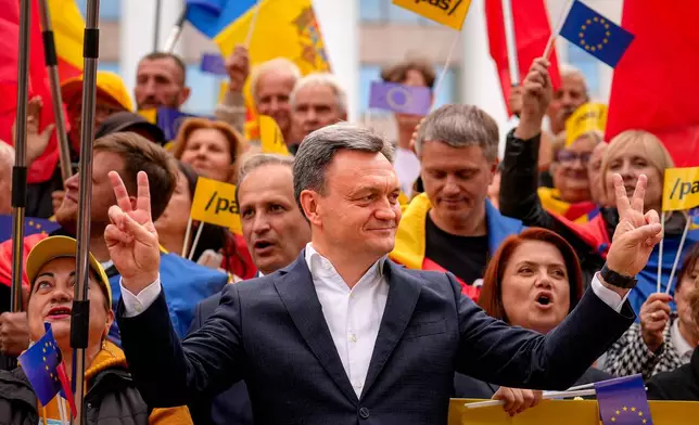 Moldova's Prime Minister Dorin Recean flashes the victory sign next to supporters during a pro-EU rally of the ruling Party of Action and Solidarity (PAS), in Chisinau, Moldova, Friday, Sept. 26, 2025, ahead of parliamentary elections taking place on Sept. 28. (AP Photo/Vadim Ghirda)