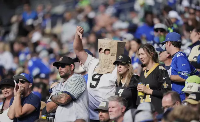 A New Orleans Saints fan wears a bag on his head and gestures in the second half of an NFL football game against the Seattle Seahawks, Sunday, Sept. 21, 2025, in Seattle. (AP Photo/Stephen Brashear)