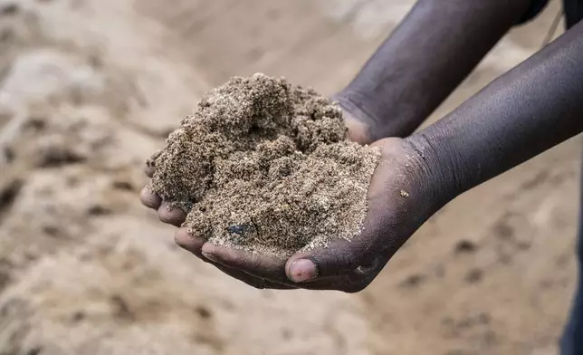 Feluzi Makono holds soil at his grandmother's farm in Mulanje, southern Malawi, Tuesday, July 29, 2025. (AP Photo/Thoko Chikondi)