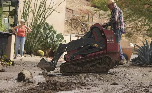 Residents clean up the damage caused by mudslides after storms in Yucaipa, Calif., Friday, Sept. 19, 2025. (AP Photo/Damian Dovarganes)