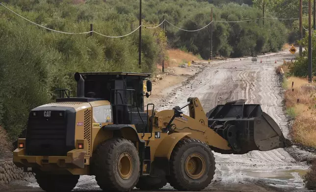 Workers clean up the damage caused by mudslides after storms in Yucaipa, Calif., Friday, Sept. 19, 2025. (AP Photo/Damian Dovarganes)