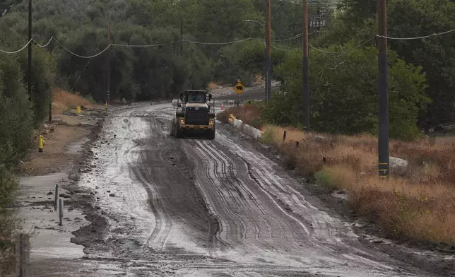 Workers clean up the damage caused by mudslides after storms in Yucaipa, Calif., Friday, Sept. 19, 2025. (AP Photo/Damian Dovarganes)
