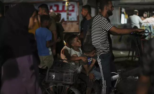 Palestinian children ride a bicycle in an area near the beachfront at a tent camp for displaced people in the Gaza City port, Tuesday, Sept. 2, 2025. (AP Photo/Jehad Alshrafi)