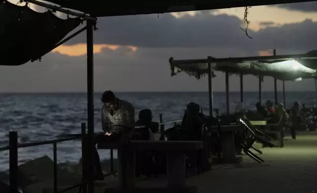 A Palestinian man looks at his phone as he stands at the seafront next to a tent camp in the Gaza City port, Tuesday, Sept. 2, 2025. (AP Photo/Jehad Alshrafi)