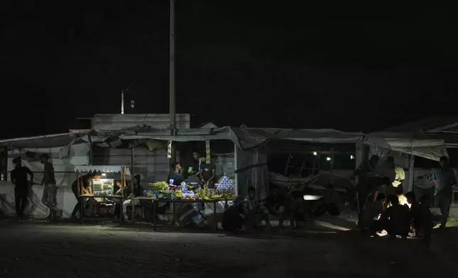 Palestinian vendors talk as they gather at a food stand near the beachfront at a tent camp for displaced people in the Gaza City port, Tuesday, Sept. 2, 2025. (AP Photo/Jehad Alshrafi)