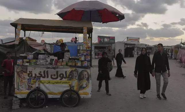 A Palestinian couple hold hands as they walk near the beachfront at a tent camp for displaced people in the Gaza City port, Tuesday, Sept. 2, 2025. (AP Photo/Jehad Alshrafi)