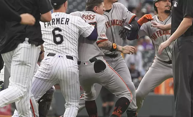 San Francisco Giants players pursue Colorado Rockies starting pitcher Kyle Freeland after he exchanged words with the Giants' Rafael Devers following Devers' two-run home run in the first inning of a baseball game Tuesday, Sept. 2, 2025, in Denver. (AP Photo/David Zalubowski)