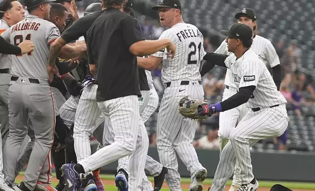 Colorado Rockies pitcher Kyle Freeland (21) is protected by teammates as members of the San Francisco Giants pursue after Freeland exchanged words with the Giants' Rafael Devers in the first inning of a baseball game Tuesday, Sept. 2, 2025, in Denver. (AP Photo/David Zalubowski)