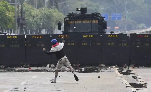 A protester throws rock at the police during a protest against lavish allowances given to parliament members, outside the parliament in Jakarta, Indonesia, Sunday, Aug. 31, 2025. (AP Photo/Dita Alangkara)