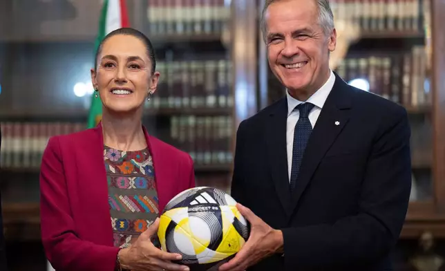Canada's Prime Minister Mark Carney, right, presents Mexican President Claudia Sheinbaum with an official World Cup soccer ball before they meet at the Palacio National in Mexico City, Thursday, Sep 18, 2025. (Adrian Wyld/The Canadian Press via AP)