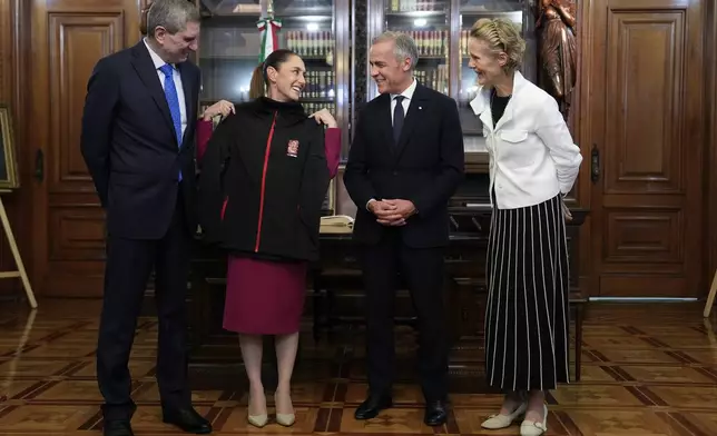 Diana Fox Carney, right, and Jesus Maria Tarriba, left, look on as Canada's Prime Minister Mark Carney presents Mexican President Claudia Sheinbaum with a World Cup sweater before a meeting at the National Palace in Mexico City, Thursday, Sept. 18, 2025. (Adrian Wyld/The Canadian Press via AP)