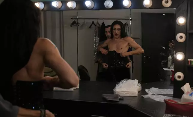 Alexandre Paulikevitch is helped into his dress by an assistant backstage before performing at a theatre in Beirut, Lebanon, Thursday, Sept. 11, 2025. (AP Photo/Hussein Malla)