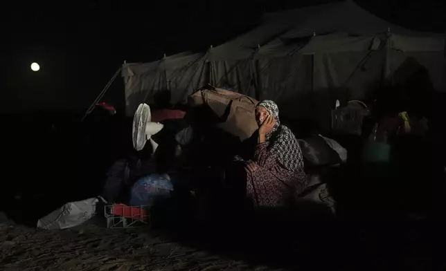 Awatif Abu Jarad, 57, sits beside her family's belongings in Khan Younis, Gaza Strip, Sept. 10, 2025, after fleeing Gaza City following evacuation orders issued by the Israeli army. (AP Photo/Abdel Kareem Hana)