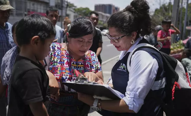 A relative of an unaccompanied minor deported from the United States reviews the list of those deported outside La Aurora International Airport, in Guatemala City, Sunday, Aug. 31, 2025. (AP Photo/Moises Castillo)