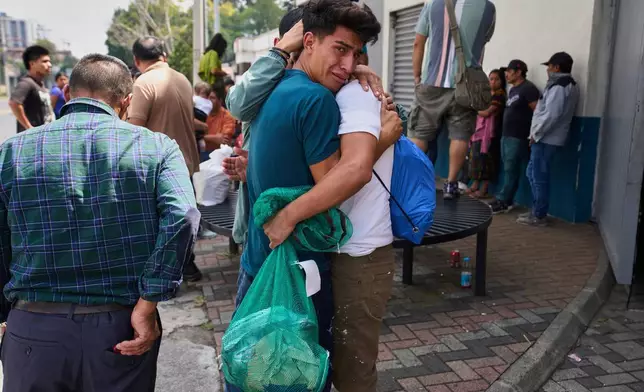 A Guatemalan migrant, in white, is embraced by an emotional relative after being deported from the United States, outside La Aurora International Airport, in Guatemala City, Sunday, Aug. 31, 2025. (AP Photo/Moises Castillo)