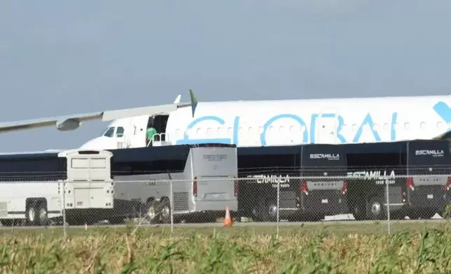 A person boards a plane in Harlingen, Texas Sunday, Aug. 31, 2025, as four charter buses are pulled into the side of the airport to unload dozens of passengers. (AP Photo/Valerie Gonzalez)