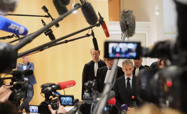 Former French President Nicolas Sarkozy speaks with the media after a Paris court sentenced him to 5 years after finding him guilty of criminal conspiracy in an alleged scheme to finance his 2007 campaign with funds from Libya, Thursday, Sept. 25, 2025 in Paris. (AP Photo/Christophe Ena)