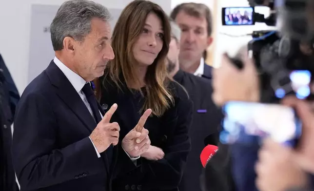 Former French President Nicolas Sarkozy, next to his wife Carla Bruni Sarkozy, speaks after a Paris court sentenced him to 5 years in prison and said he'll be incarcerated even if he appeals, after finding him guilty in his trial for alleged illegal campaign financing by Libya, Thursday, Sept. 25, 2025 in Paris. (AP Photo/Michel Euler)