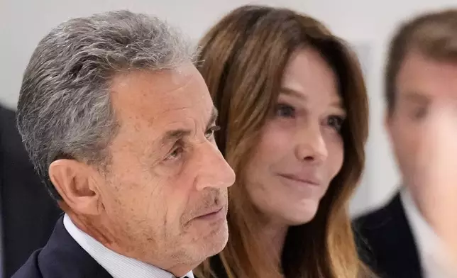 Former French President Nicolas Sarkozy, next to his wife Carla Bruni Sarkozy, speaks after a Paris court sentenced him to 5 years in prison and said he'll be incarcerated even if he appeals, after finding him guilty in his trial for alleged illegal campaign financing by Libya, Thursday, Sept. 25, 2025 in Paris. (AP Photo/Michel Euler)
