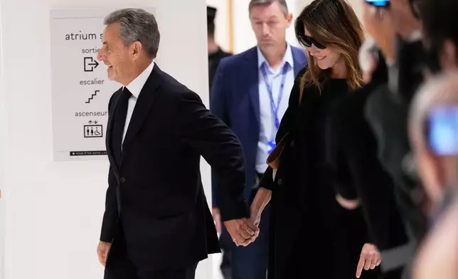 Former French President Nicolas Sarkozy and his wife Carla Bruni Sarkozy arrive to the courtroom for his verdict for alleged illegal financing of his 2007 presidential campaign by the government of then-Libyan leader Moammar Gadhafi, Thursday, Sept. 25, 2025 in Paris. (AP Photo/Michel Euler)