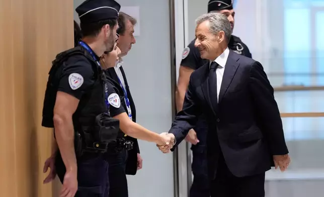 Former French President Nicolas Sarkozy shakes hands with a police officer before his verdict for alleged illegal financing of his 2007 presidential campaign by the government of then-Libyan leader Moammar Gadhafi, Thursday, Sept. 25, 2025 in Paris. (AP Photo/Michel Euler)