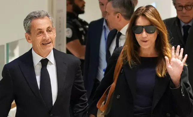 Former French President Nicolas Sarkozy, left, and his wife Carla Bruni, right, arrive at the courthouse, in Paris, France, Thursday, Sept. 25, 2025. (AP Photo/Christophe Ena)