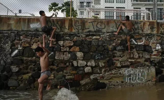Youths climb a colonial-era wall to dive into the sea in the "Casco Viejo," the historic district of Panama City, a UNESCO World Heritage Site, Sunday, Aug. 10, 2025. (AP Photo/Matias Delacroix)