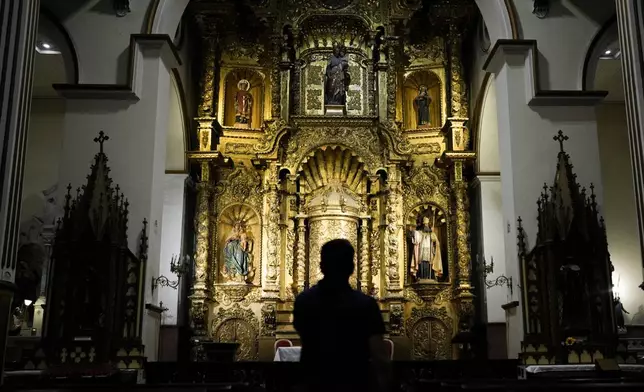 A tourist stands at the Golden Altar inside Saint Joseph Church, a baroque piece covered in gold leaf built in the 17th century after Panama City was relocated from its first settlement destroyed by pirates, in "Casco Viejo," the historic district of Panama City, Friday, Aug. 15, 2025. (AP Photo/Matias Delacroix)