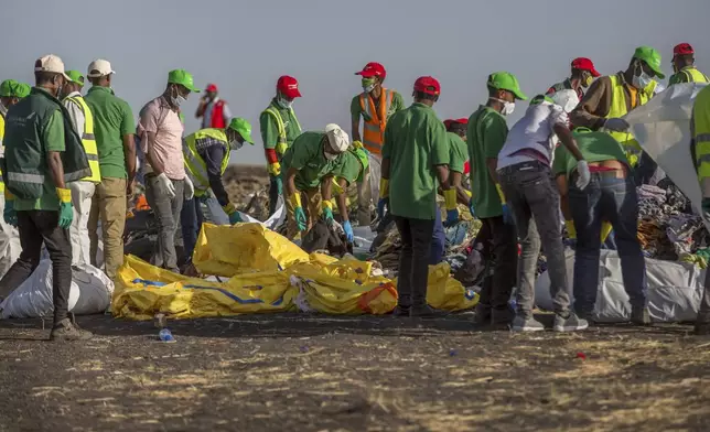 FILE - Workers collect debris on March 12, 2019 at the scene where an Ethiopian Airlines Boeing 737 Max 8 crashed shortly after takeoff, killing all 157 on board, near Bishoftu, or Debre Zeit, south of Addis Ababa, in Ethiopia. (AP Photo/Mulugeta Ayene, File)