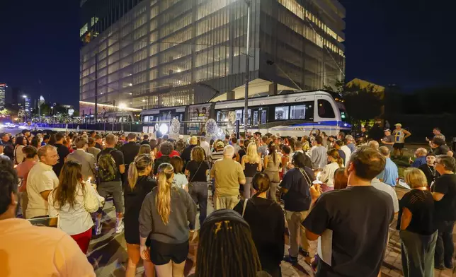 A light rail train passes by as community members gather for a vigil honoring the life of Iryna Zarutska, who was fatally stabbed on a commuter train last month, Monday, Sept. 22, 2025, in Charlotte, N.C. (AP Photo/Nell Redmond)