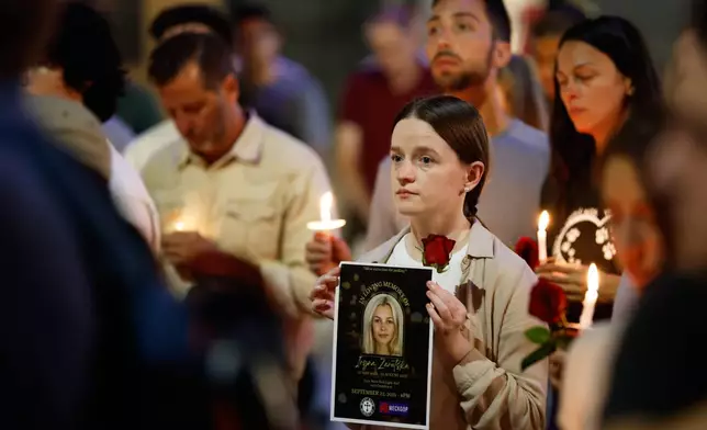 Community members hold flyers and candles as they gather for a vigil honoring the life of Iryna Zarutska, who was fatally stabbed on a commuter train last month, Monday, Sept. 22, 2025, in Charlotte, N.C. (AP Photo/Nell Redmond)