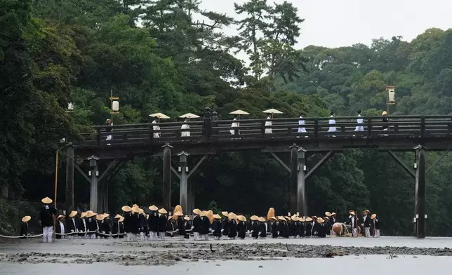 Shinto priests and officials in the priesthood walk on the Uji bridge, as people pull a sacred timber in the Isuzu river towards Kotaijingu, also known as Naiku, or the inner sanctuary of the Ise Jingu shrine complex, during the Mihishirogi Hoeishiki ceremony of the Shikinen Sengu ritual to rebuild its main structures for Shinto deities, in Ise, central Japan, Monday, June 9, 2025. (AP Photo/Hiro Komae)