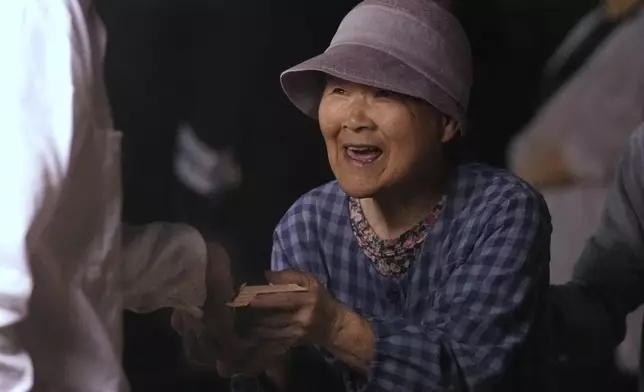 Fumiko Fujita receives pieces of a sacred timber felled in a forest early morning during Misomahajimesai, an early ceremony of the Shikinen Sengu ritual to rebuild main structures of the Ise Jingu shrine for Shinto deities, in Agematsu, central Japan, Tuesday, June 3, 2025. (AP Photo/Hiro Komae)