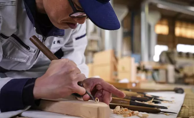 A craftsman uses a chisel while making a Shinto shrine alter at Miyachu factory, which also crafts miniature replicas of the Ise Jingu shrine, in Tamaki, central Japan, Thursday, May 1, 2025. (AP Photo/Hiro Komae)