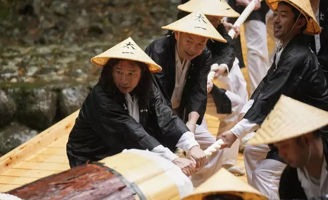 People carry a hinoki timber, Japanese cypress, into the Ise Jingu shrine complex during a festivity called Mihishirogi Hoeishiki in Ise, central Japan, Monday, June 9, 2025. (AP Photo/Hiro Komae)