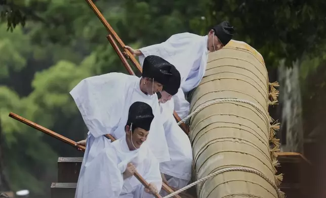 Members of the Shinto priesthood try to push down a sacred timber from a wheeled platform at the end of Mihishirogi Hoeishiki, a ceremony of the Shikinen Sengu ritual to rebuild the shrine's main structures for Shinto deities, at the Ise Jingu shrine complex, in Ise, central Japan, Tuesday, June 10, 2025. (AP Photo/Hiro Komae)
