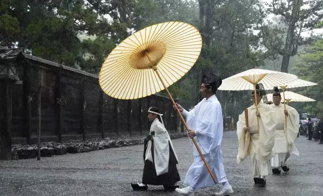 Shinto priests and a girl called "monoimi" march into the main palace of Toyoukedaijingu, also known as Geku, or the outer sanctuary, of the Ise Jingu shrine complex as they begin Yamaguchisai, a kickoff ceremony of Shikinen Sengu, which concludes in 2033, in Ise, central Japan, Friday, May 2, 2025. (AP Photo/Hiro Komae)