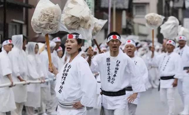 People lead a procession of pulling a sacred timber towards Toyoukedaijingu, also known as Geku, or the outer sanctuary of the Ise Jingu shrine complex, during the Mihishirogi Hoeishiki ceremony of the Shikinen Sengu ritual to rebuild its main structures for Shinto deities, in Ise, central Japan, Tuesday, June 10, 2025. (AP Photo/Hiro Komae)