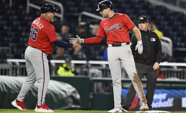 Atlanta Braves' Matt Olson, right, celebrates with third base coach Fredi González (86) after hitting a triple to drive in three runs during the 10th inning of the second baseball game of a doubleheader against the Washington Nationals, Tuesday, Sept. 16, 2025, in Washington. (AP Photo/Nick Wass)