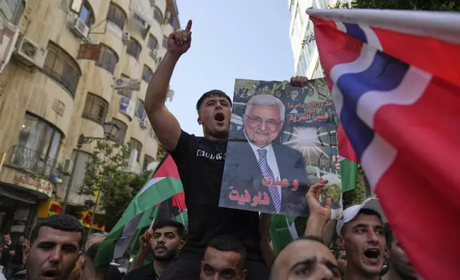 Palestinians chant national slogans and carry posters with pictures of President Mahmoud Abbas and read "you kept your promise," during a rally in support for Gaza and celebrating the latest western nations recognitions of the Palestinian state ahead of the United Nations General Assembly meetings, in the West Bank city of Ramallah Tuesday, Sept. 23, 2025. (AP Photo/Nasser Nasser)