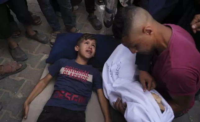 Omar Al-Zaqzouq, 7, mourns over the body of his 2-year-old brother Malek, who was killed in an Israeli military strike, during his funeral outside Al-Aqsa Hospital in Deir al-Balah, in the central Gaza Strip, Monday, Sept. 22, 2025. (AP Photo/Abdel Kareem Hana)