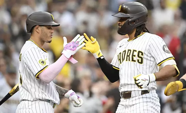 San Diego Padres' Fernando Tatis Jr., right, is congratulated by Manny Machado (13) after hitting a solo home run during the second inning of a baseball game against the Colorado Rockies Saturday, Sept. 13, 2025, in San Diego. (AP Photo/Denis Poroy)