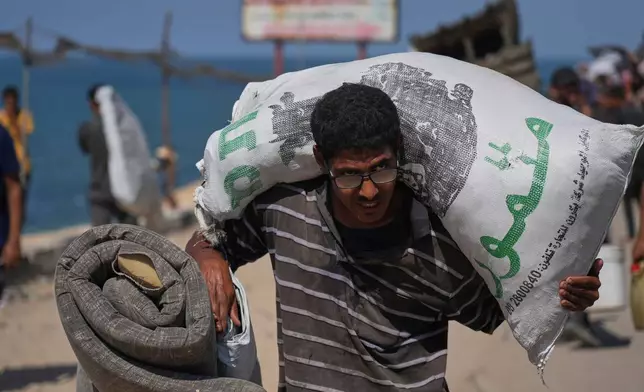 A displaced Palestinian flees northern Gaza Strip, carrying his belongings along the coastal road, near Wadi Gaza, Tuesday, Sept. 23, 2025. (AP Photo/Abdel Kareem Hana)