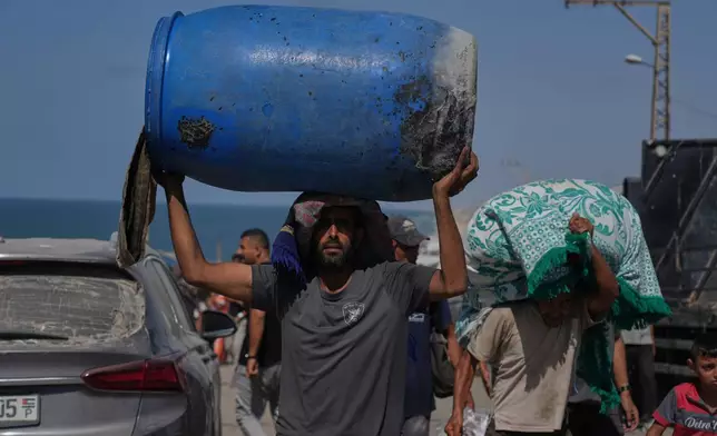 Displaced Palestinians flee northern Gaza Strip, carrying their belongings along the coastal road, near Wadi Gaza, Tuesday, Sept. 23, 2025. (AP Photo/Abdel Kareem Hana)