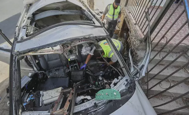 Civil defense workers inspect a damaged car hit Sunday in an Israeli drone strike that killed four members of the same family, in Bint Jbeil town, southern Lebanon, Monday, Sept. 22, 2025. (AP Photo/Mohammed Zaatari)