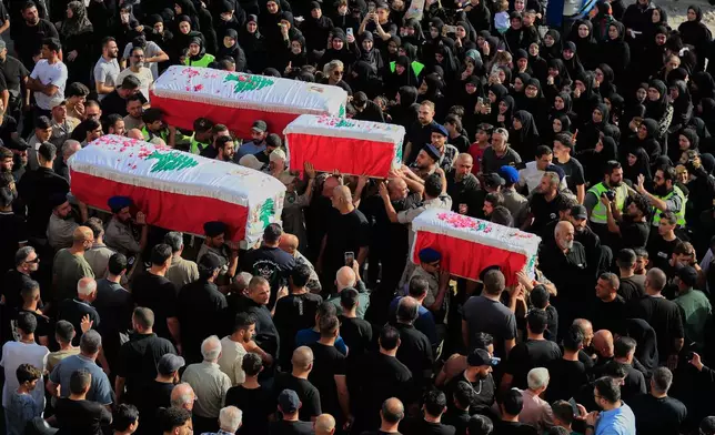 Mourners carry the coffins of four family members killed Sunday in an Israeli drone strike that hit their car, during a funeral procession in Bint Jbeil, southern Lebanon, Tuesday, Sept. 23, 2025. (AP Photo/Mohammed Zaatari)