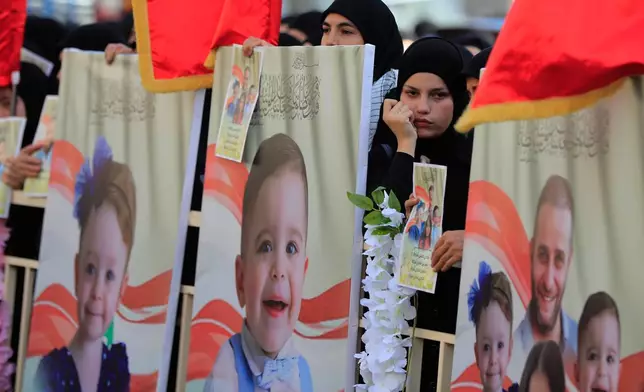 A woman stands next to portraits of Shadi Charara and three of his children killed Sunday in an Israeli drone strike that hit their car, during a funeral procession in Bint Jbeil, southern Lebanon, Tuesday, Sept. 23, 2025. (AP Photo/Mohammed Zaatari)